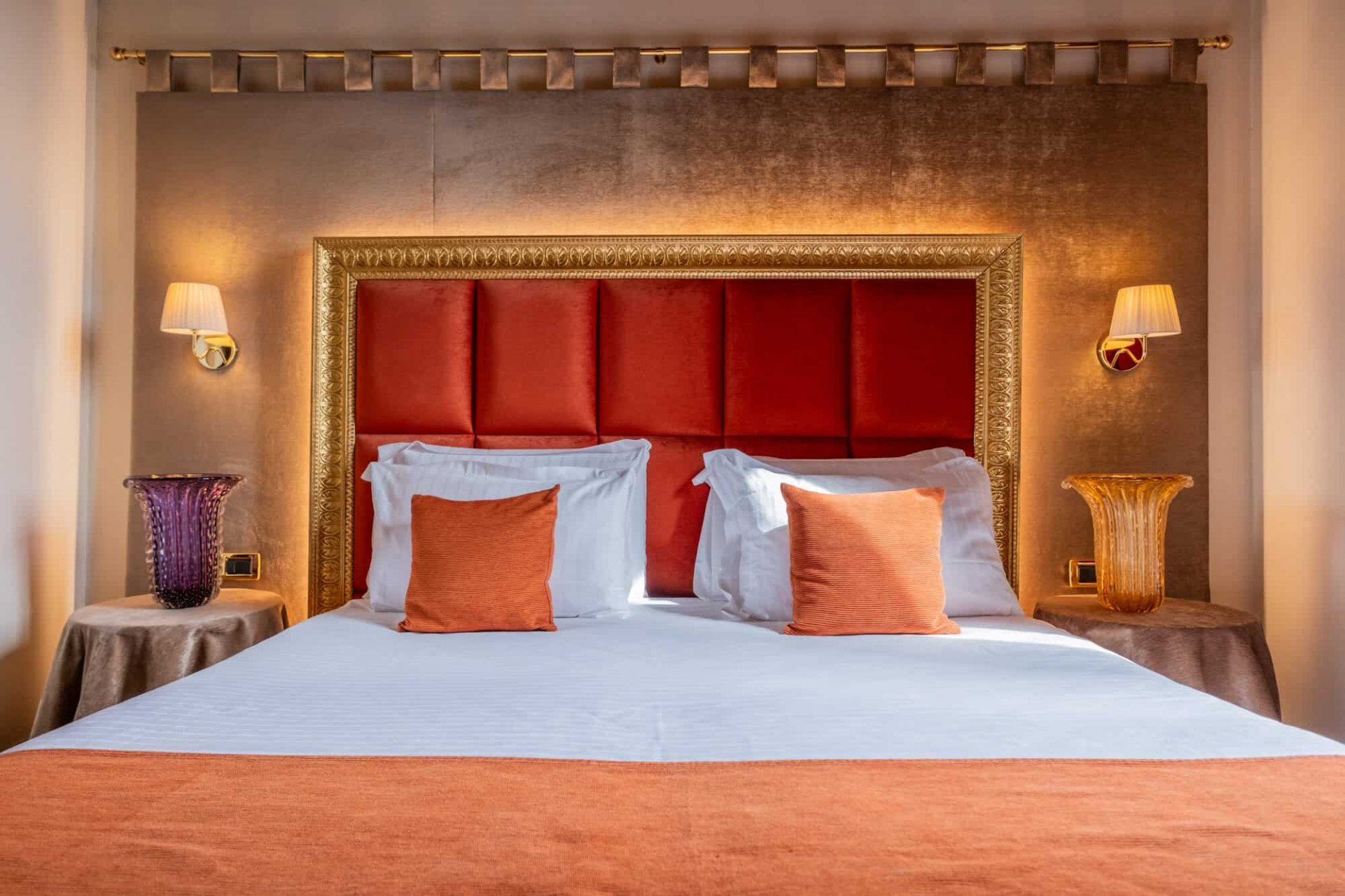 Elegant room with gold, orange, and red details and a comfortable bed 